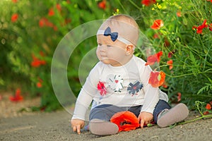 Portrait of a beautiful little girl having fun in field of red poppy flowers in spring.