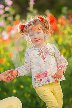 Portrait of a beautiful little girl having fun in field of red poppy flowers in spring.