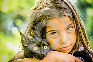 Portrait of a beautiful little girl holding a black cat