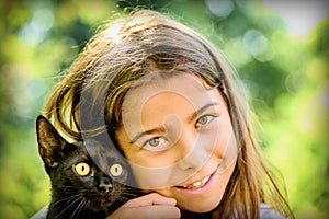 Portrait of a beautiful little girl holding a black cat