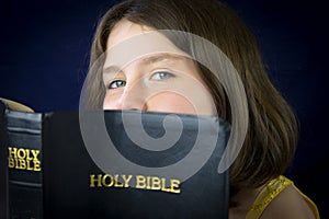 Portrait of beautiful little girl holding Holy Bible
