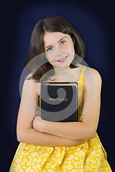 Portrait of beautiful little girl holding Holy Bible