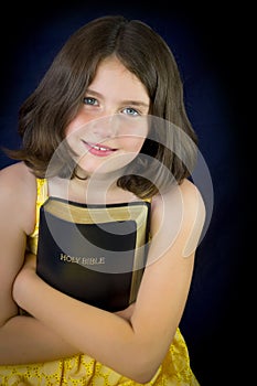 Portrait of beautiful little girl holding Holy Bible