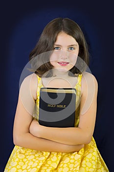 Portrait of beautiful little girl holding Holy Bible