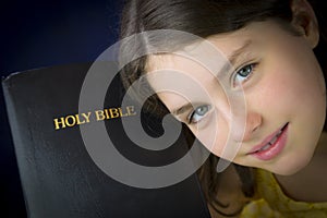 Portrait of beautiful little girl holding Holy Bible