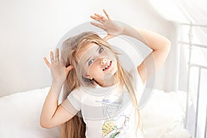 Portrait of a beautiful little girl with long curly hair, smiling at the camera, making funny faces. Cute funny charming joyful bl