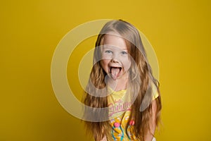 Portrait of beautiful little girl with long hair smiling posing isolated at yellow studio background