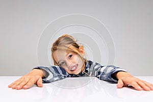 Portrait of beautiful little girl looking at camera, making faces isolated on gray studio background. Human emotions