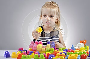 Portrait of beautiful little girl playing with plastic toy cubes