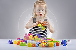 Portrait of beautiful little girl playing with plastic toy cubes