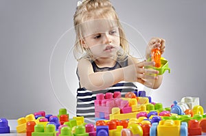 Portrait of beautiful little girl playing with plastic toy cubes