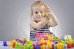 Portrait of beautiful little girl playing with plastic toy cubes