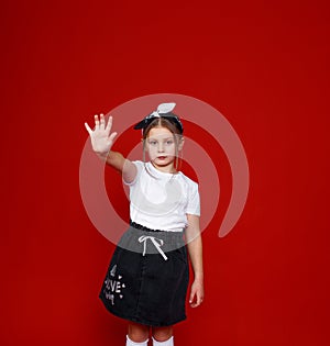 Portrait of a beautiful little girl posing on an isolated red background. extend your arm forward stop