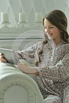Portrait of beautiful little girl with tablet pc on sofa