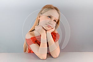 Portrait of a beautiful little sad blond girl in a white shirt, isolated on a white background.