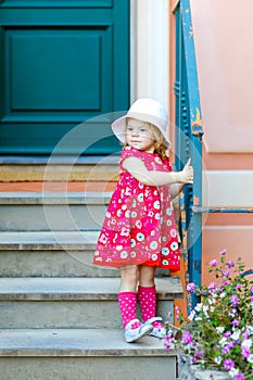 Portrait of beautiful little toddler girl in pink summer look clothes, fashion dress, knee socks and hat. Happy healthy