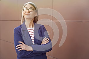 Portrait of a beautiful mature business woman wearing eyeglasses and classic wear keeping arms crossed and looking aside