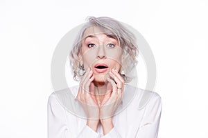 Portrait of a beautiful mature woman looking at camera with open mouth and hands at her face surprised and shocked