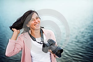 Portrait of beautiful mature woman on vacation, taking photos with professional camera, capturing beauty in nature photo