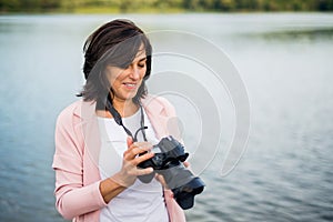 Portrait of beautiful mature woman on vacation, taking photos with professional camera, capturing beauty in nature photo