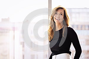 Portrait of a beautiful mid aged woman with blond hair wearing business casual while standing at glasswall