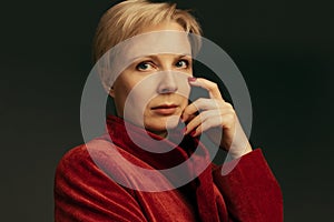 Portrait of beautiful middle-aged woman in stylish red velvet jacket posing isolated over dark background. Businesswoman