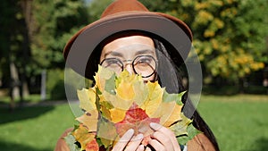 Portrait of a beautiful middle eastern smiling woman holding a bouquet of colorful leaves in her hands. Autumn leaves in