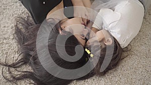 Portrait of a beautiful middle eastern young woman laying with her daughter at the soft carpet and talking. Happy mother