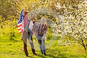 portrait of beautiful modern american family with USA flag outdoors.