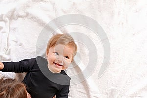 Portrait of beautiful mom playing with her baby in bedroom