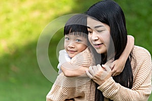 Portrait beautiful mother and child happily hugged in park. Asian family mom and child are hugging and looking at the camera, cute