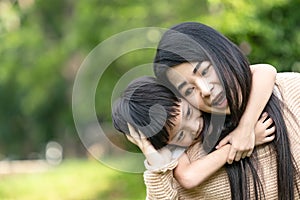 Portrait beautiful mother and child happily hugged in park. Asian family mom and child are hugging and looking at the camera, cute