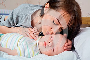 Portrait of beautiful mother with her 7 months old baby sleeping