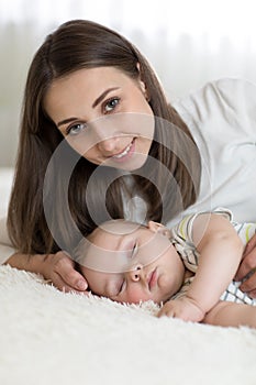Portrait of beautiful mother with her 7 months old baby sleeping in the bed