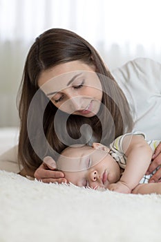 Portrait of beautiful mother with her 7 months old baby sleeping in the bed