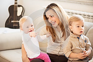 Portrait of beautiful mother and her children sitting in the lap. Little baby girl pointing with finger.