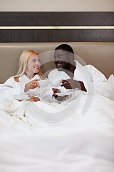 Portrait of beautiful multiethnic couple drinking tea on bed