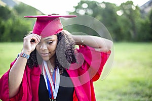 Portrait of a beautiful multiethnic woman putting on her graduation cap and gown photo