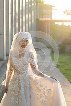 Portrait of a beautiful muslim bride with make up in white wedding dress with beautiful white headdress natural light.