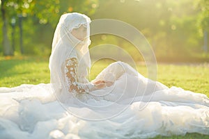 Portrait of a beautiful muslim bride with make up in white wedding dress with beautiful white headdress natural light.