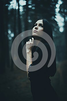 Portrait of a beautiful mysterious woman in the forest. Cold ton