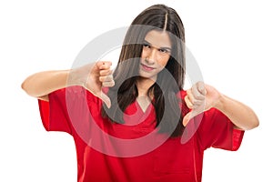 Portrait of beautiful nurse wearing red scrubs showing thumbs down