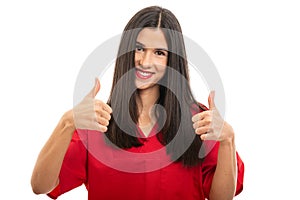 Portrait of beautiful nurse wearing red scrubs showing thumbs up