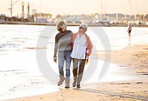 Portrait of beautiful older mom and mature daughter walking on the beach at autumn sunset