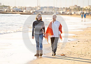 Portrait of beautiful older mom and mature daughter walking on the beach at autumn sunset