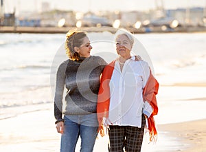 Portrait of beautiful older mom and mature daughter walking on the beach at autumn sunset