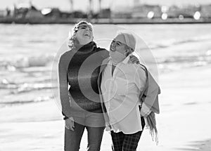 Portrait of beautiful older mom and mature daughter walking on the beach at autumn sunset