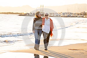 Portrait of beautiful older mom and mature daughter walking on the beach at autumn sunset