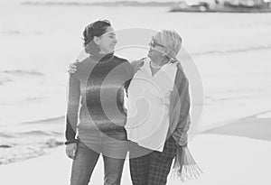 Portrait of beautiful older mom and mature daughter walking on the beach at autumn sunset