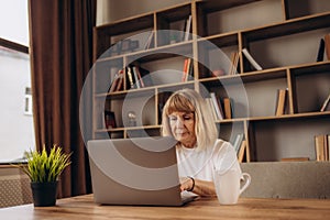 Portrait of beautiful older woman working laptop computer indoors